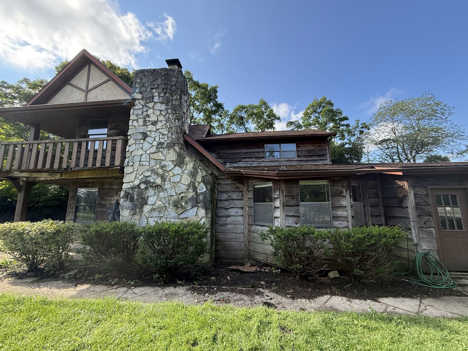Wood-sided home in Central Ohio before washing — the timber weathered silver-grey and algae staining the stone chimney