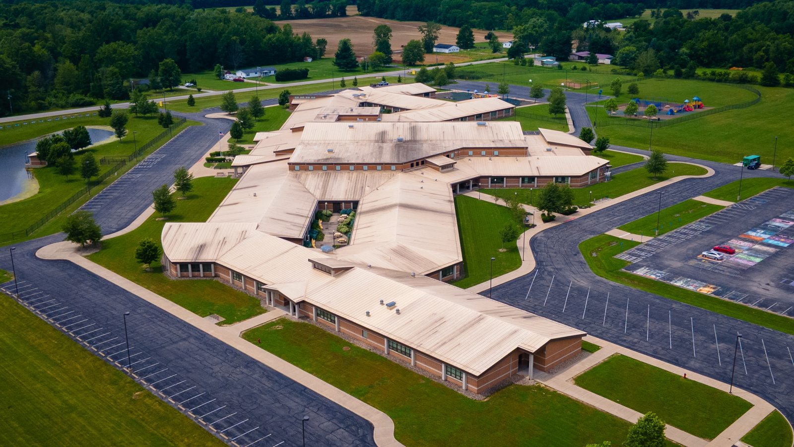 Aerial view of a Central Ohio school roof before washing, streaked and weathered across every wing