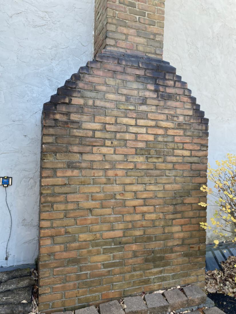 Brick chimney on a stucco home before washing