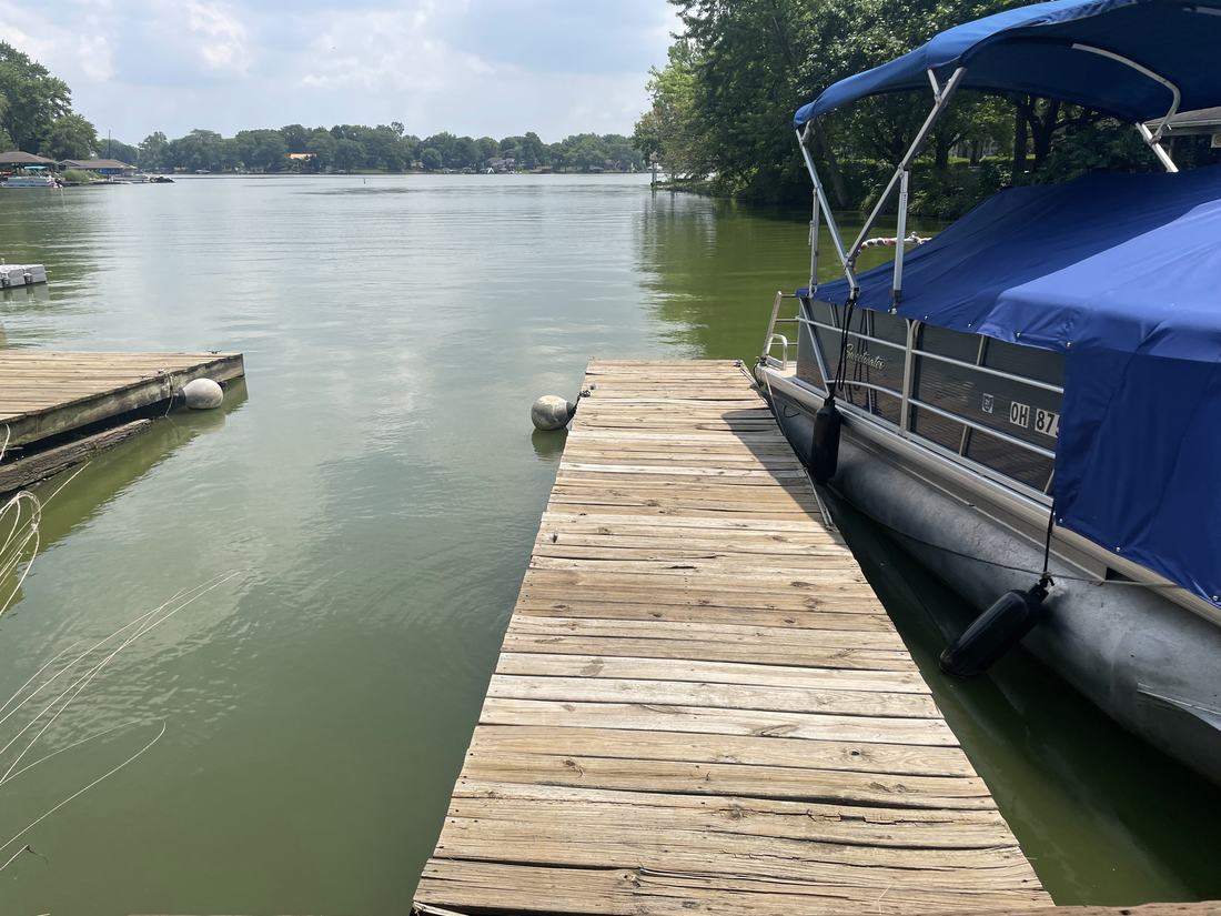 Washed wooden boat dock beside a pontoon boat on a Central Ohio lake