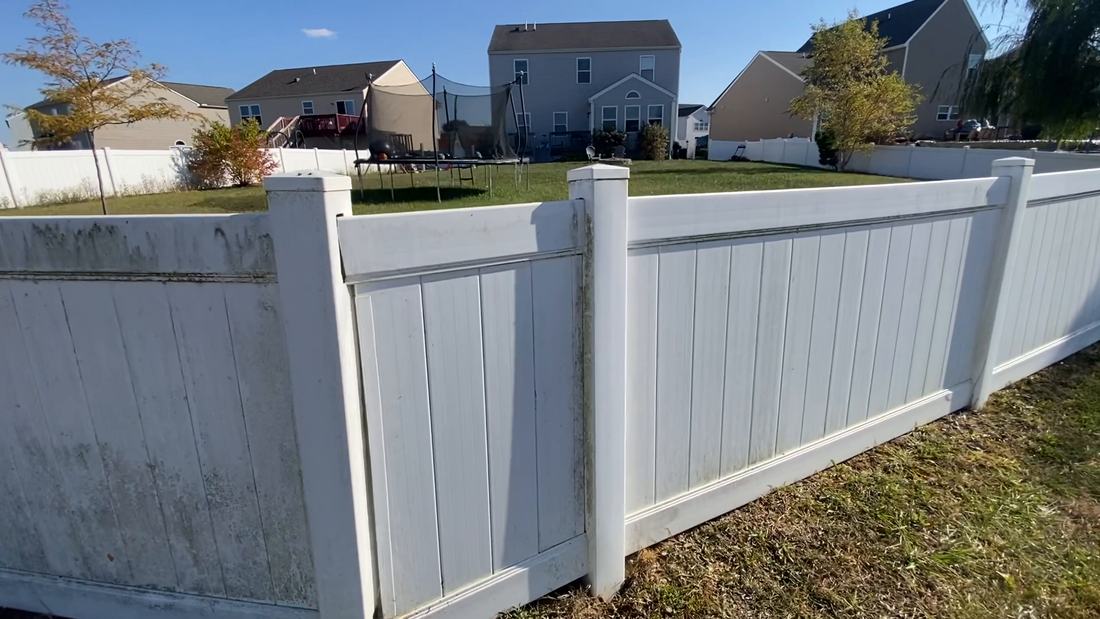Vinyl fence mid-wash, stained panels beside cleaned ones, in Central Ohio