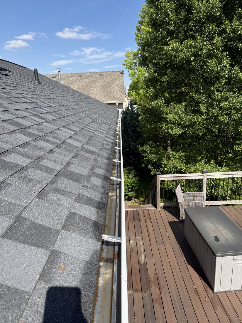 Cleared gutter run along a shingle roof edge above a deck in Central Ohio
