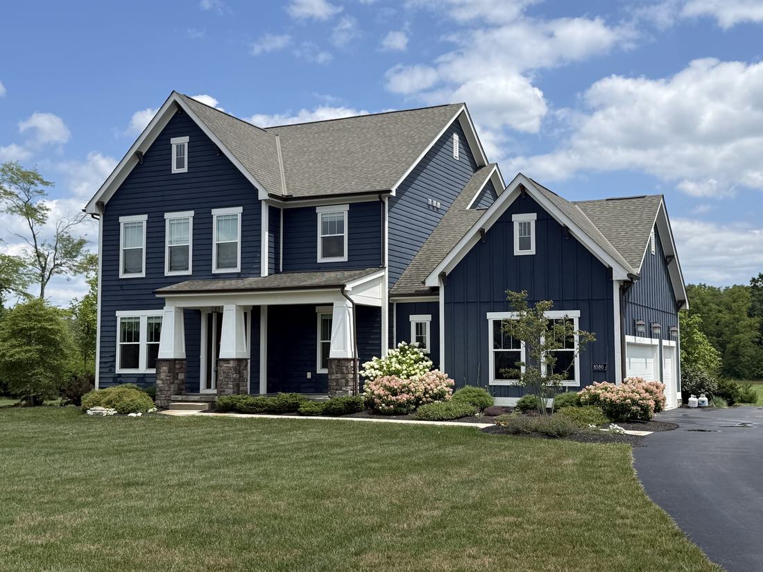 Navy board-and-batten farmhouse with clean siding and stonework in Central Ohio