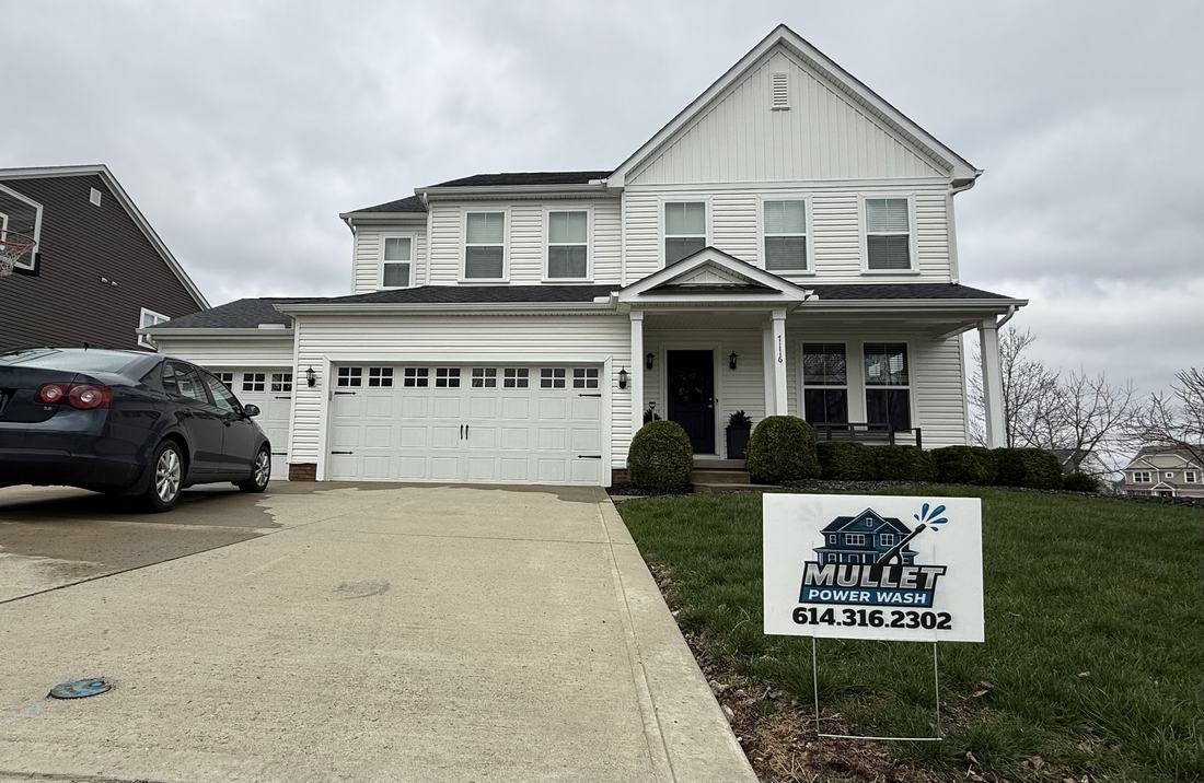 White two-story home washed by Mullet Power Wash, with the company yard sign out front