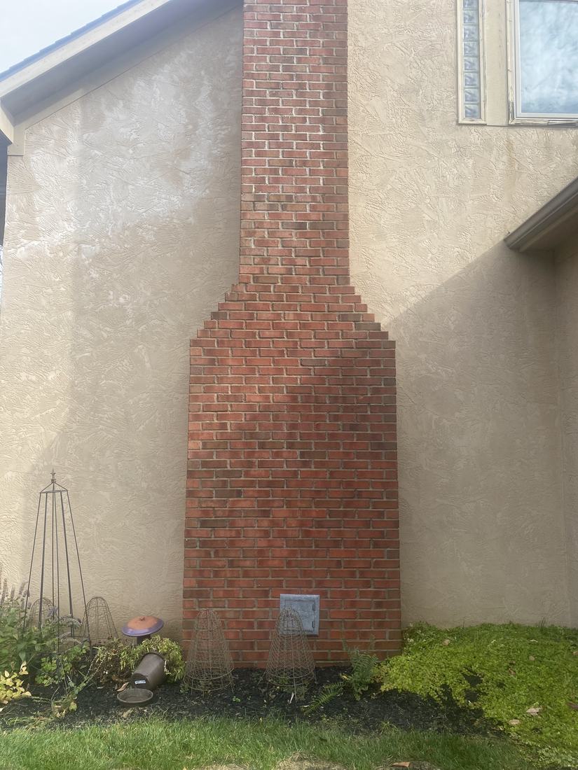 Stucco wall and brick chimney after washing by Mullet Power Wash