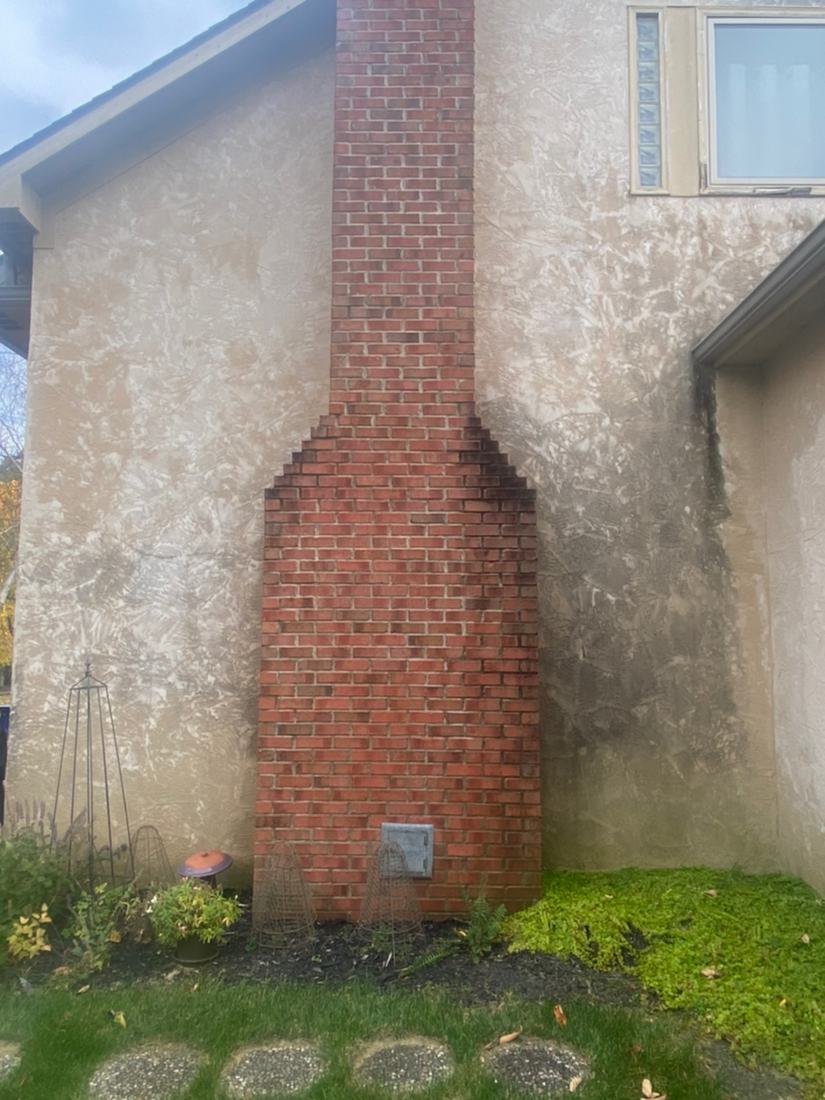 Stucco wall and brick chimney before washing