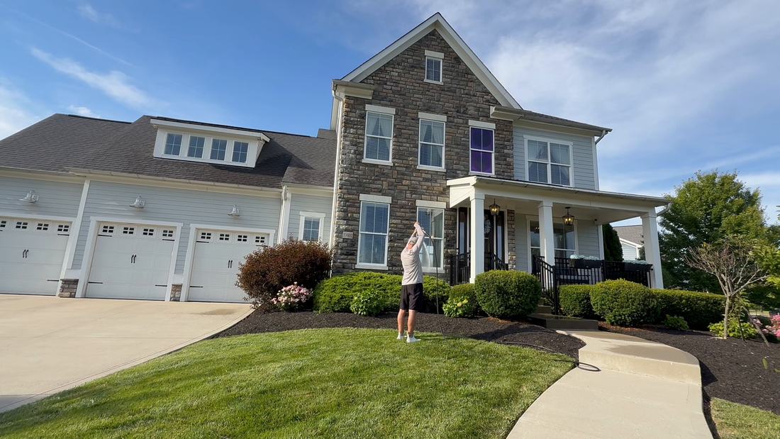 Window washing with a water-fed pole on a stone-front two-story home in Central Ohio
