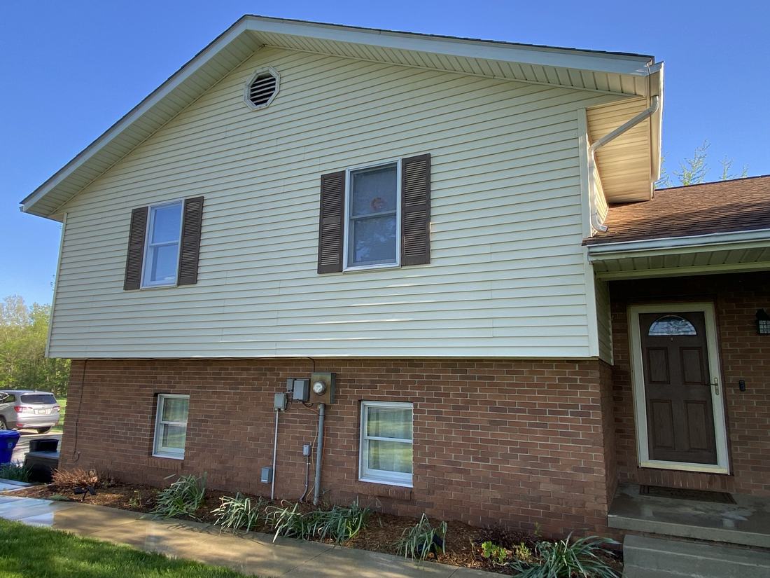 Yellow siding over brick after washing by Mullet Power Wash